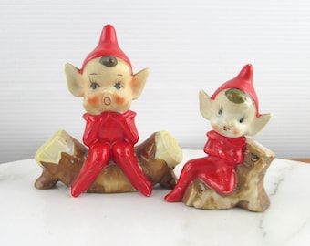 2 süße Vintage-Keramik-Pixie-Figuren in roten Anzügen auf Baumstämmen, kitschige Elfenfigur, 1950er Jahre, hergestellt in Japan