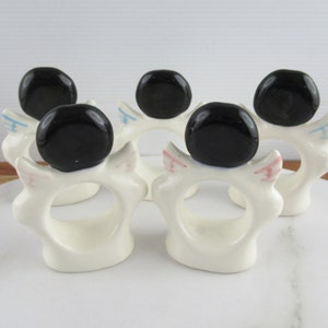 Puede incluir: Conjunto de cinco anillos de servilleta de cer&aacute;mica blanca con tapas de cer&aacute;mica negra. Cada anillo tiene un dise&ntilde;o rosa y azul en el lateral.