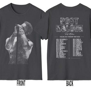 May include: Dark gray t-shirt featuring a black and white image of a person on the front. The back of the shirt displays the text "POST MALONE" and "THE BIG ASS STADIUM TOUR 2026" with a list of tour dates.