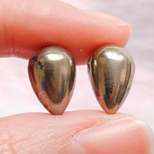 Può includere: Un paio di orecchini d'argento a forma di lacrima. Gli orecchini sono lisci e lucidi.