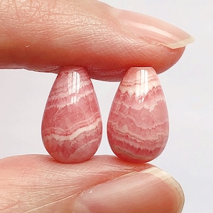 Può includere: Due perle di pietra preziosa a forma di goccia, rosa e bianche.