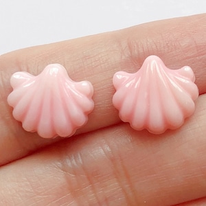 Può includere: Due cabochon in resina di forma a conchiglia rosa. I cabochon sono lisci e lucidi.