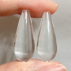 Può includere: Due perline di vetro trasparenti a forma di goccia.