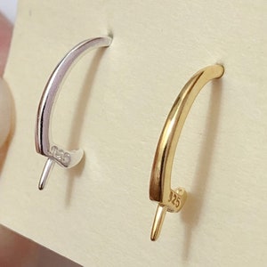 May include: Two hoop earrings, one silver and one gold, are displayed on a white card. Both earrings have a small, pointed end and are marked with "925".
