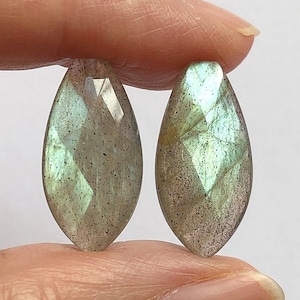 Può includere: Due pietre preziose di labradorite verde a forma di pera con bagliori iridescenti.