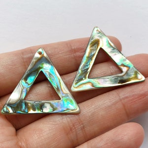 May include: Two iridescent green and gold triangle shaped shell pendants with a hole at the top for hanging.