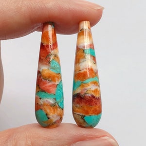 Può includere: Due cabochon di pietra turchese e corallo a forma di lacrima. Le pietre sono un mix di arancione, rosso, bianco e turchese.