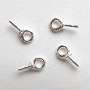 May include: Four silver jump rings with a pin attached to each ring. The rings are about 1/2 inch in diameter.