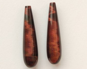 May include: Two teardrop-shaped red tiger's eye gemstone beads. The beads have a dark brown and red color with a subtle shimmer.