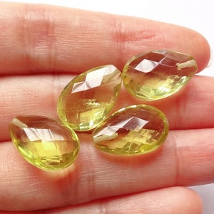 Può includere: Quattro pietre preziose sfaccettate a forma di lacrima di colore giallo pallido. Le pietre preziose sono esposte su una mano.