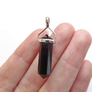 Pode incluir: Pingente de cristal de ponta de obsidiana preta com uma fivela de prata. O pingente tem aproximadamente 3,8 cm de comprimento.
