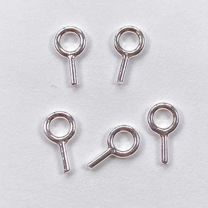 May include: Six silver jump rings with a small loop at the top and a straight pin at the bottom.