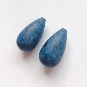May include: Two teardrop-shaped blue gemstone beads with a mottled pattern.