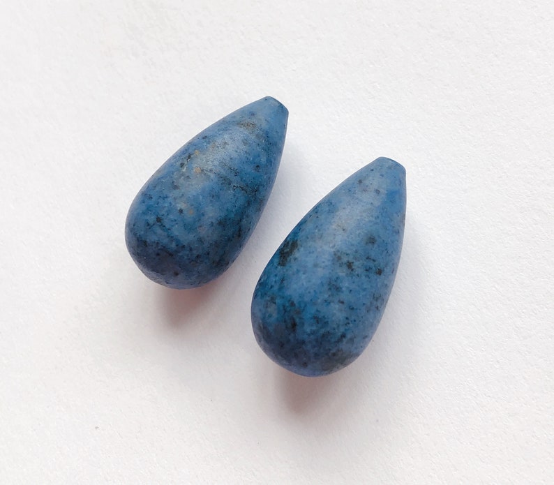 May include: Two teardrop-shaped blue gemstone beads with a mottled pattern.