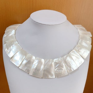 May include: A white mother-of-pearl necklace with rectangular shaped beads.