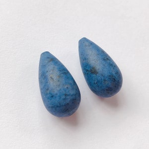May include: Two teardrop-shaped blue ceramic beads with a speckled finish.