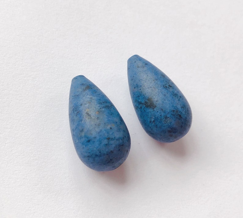 May include: Two teardrop-shaped blue ceramic beads with a speckled finish.