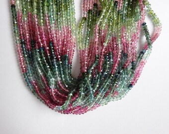 Pode incluir: Um fio de contas de pedras preciosas multicoloridas. As contas são facetadas e têm uma variedade de tons de rosa, verde e azul.