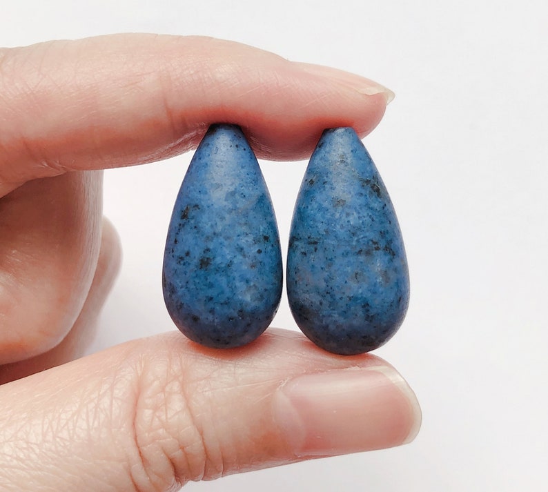May include: A pair of teardrop-shaped earrings made of blue speckled clay.