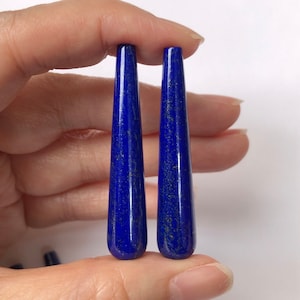 Può includere: Due cabochon lunghi e appuntiti in lapislazzuli blu scuro con macchie dorate.