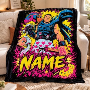 May include: A black fleece blanket featuring a vibrant comic-style illustration of a muscular character with a blue cape, a pink dinosaur, and a cat. The design includes a white heart-patterned garment, a stick of dynamite labelled GODDAMNIT DONUT, and the word NAME in large yellow letters.
