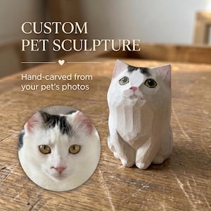 May include: A hand-carved wooden cat sculpture featuring a white coat with dark patches on the head, pointed ears, and painted eyes. The sculpture is displayed alongside a circular inset photograph of a white cat with dark head markings.