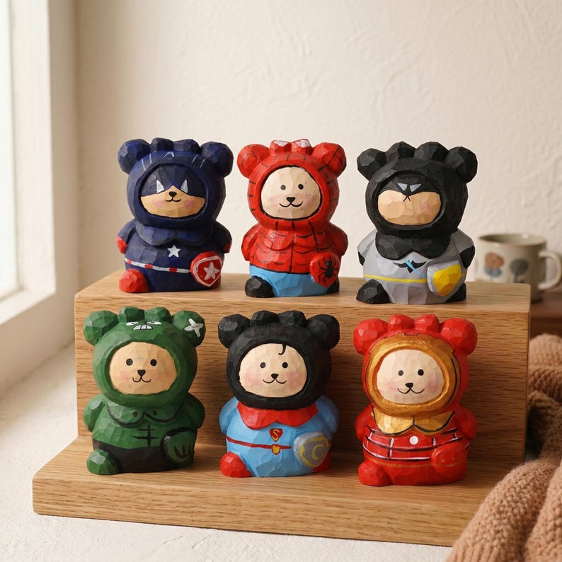 Puede incluir: Seis figuras de oso de madera talladas a mano vestidas como superh&eacute;roes. Cada oso est&aacute; pintado con colores vibrantes, incluyendo azul, rojo, verde y negro, con disfraces tem&aacute;ticos de superh&eacute;roes. Los osos se exhiben en una estanter&iacute;a de madera.
