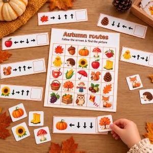 May include: An educational Autumn routes game board featuring a grid of seasonal icons like pumpkins, squirrels, and leaves. Includes several rectangular instruction cards with arrow sequences and matching square tiles for interactive play.
