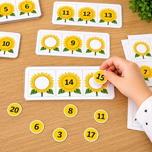May include: Educational sunflower-themed number matching cards featuring yellow flowers with black numerals. The set includes rectangular strips with three sunflowers each and separate circular tokens displaying numbers 3, 6, 8, 11, 15, 17, and 20.