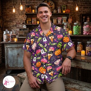 May include: A short-sleeved button-down shirt in a dark purple hue featuring a repeating pattern of Halloween-themed treats including jack-o'-lanterns, ghost-shaped popsicles, skull-topped ice cream cones, spider webs, and colorful candies.
