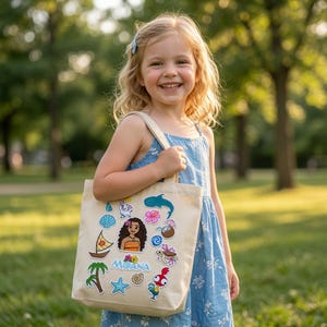May include: A beige canvas tote bag featuring embroidered patches of Moana, a sailboat, a palm tree, a starfish, a sea turtle, a coconut drink, a hibiscus flower, a whale shark, a seashell, a small white pig, a rooster, and the text Moana.