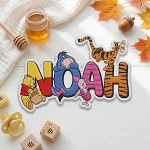 May include: An embroidered patch featuring the name NOAH in large, colorful letters. Winnie the Pooh sits by the N, Eeyore rests on the O, Piglet stands by the A, and Tigger is perched on the H. The letters are yellow, red, blue, pink, and orange.