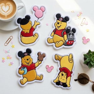 May include: Four embroidered patches featuring the character Winnie the Pooh in various poses. One patch shows Pooh holding a pink balloon, another with a backpack, one holding a honey pot and cookie, and the last one doing a handstand.