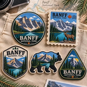 May include: Five embroidered patches featuring Banff National Park. One circular, one stamp-shaped with a deer, one shield-shaped, one bear-shaped, and one triangular patch. All display mountains, pine trees, blue lakes, and the text Banff National Park.