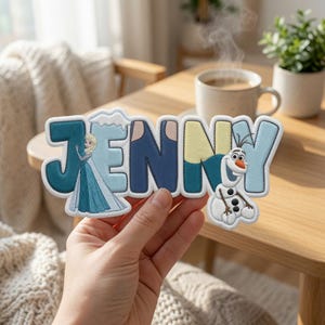 Puede incluir: Un parche bordado personalizado con el nombre JENNY en letras de bloque gruesas. La letra J incorpora la figura de un personaje rubio con vestido azul, mientras que la letra Y presenta un mu&ntilde;eco de nieve blanco con nariz de zanahoria.