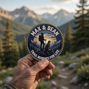 May include: A round patch with the text "MAX & BEAN" and "TRAIL BUDDIES FOR LIFE". The patch features a hiker and dog silhouette on a mountain scene, with a blue and gold color scheme.