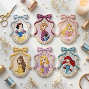 May include: Six oval embroidered patches featuring Disney princesses, each framed in a decorative border with a colored bow at the top. The characters include Snow White, Anna, Aurora, Belle, Rapunzel, and Ariel, rendered in detailed thread work.