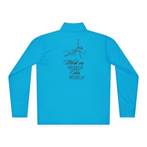 Op de afbeelding: Een turquoise sporttop met lange mouwen en een opstaande kraag. De achterkant van de top heeft een zwarte lijntekening van een persoon die paaldanst, met de tekst "Work on MYSELF For MYSELF" in zwart script.