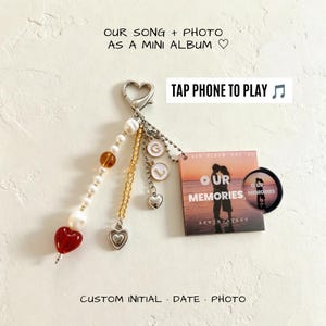 Puede incluir: Un llavero con cierre de mosquetón plateado, una cadena de cuentas blancas y ámbar con un dije de corazón rojo, una cadena de cuentas amarillas con un dije de corazón, dos dijes circulares con iniciales y un dije cuadrado con la foto y el texto OUR MEMORIES.