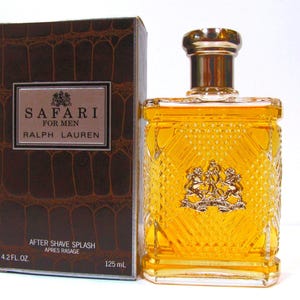 Pode incluir: Um frasco de vidro retangular de loção pós-barba Safari for Men da Ralph Lauren, com um padrão de diamante texturizado e um brasão dourado. Ao lado, uma caixa castanha com textura de pele de crocodilo, exibindo a marca e o nome do produto.