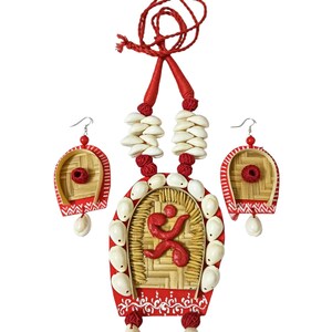 May include: A handcrafted necklace and earring set. The necklace features a red pendant with a woven center, adorned with white seashells and a red figure. Matching earrings complete the set, all on a white background.