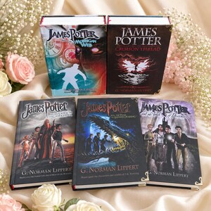 May include: A collection of five hardcover books titled James Potter by G. Norman Lippert. The titles include The Morrigan Web, The Crimson Thread, The Curse of the Gatekeeper, The Hall of Elders' Crossing, and The Vault of Destinies, featuring illustrated covers.