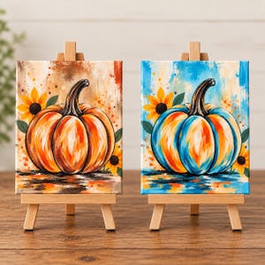 May include: Two rectangular canvases on wooden easels, each featuring a painted pumpkin and sunflowers. The left canvas displays an orange pumpkin on a warm-toned background, while the right canvas shows a blue and orange pumpkin on a blue background.