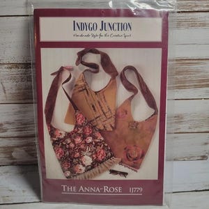 May include: A sewing pattern titled "The Anna-Rose" by Indygo Junction. The pattern features three handbag designs with floral and textured details. The pattern is packaged in a clear plastic sleeve.