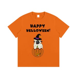 Könnte beinhalten: Ein orangefarbenes T-Shirt mit kurzen Ärmeln und einer Grafik eines weißen Schafs mit schwarzem Gesicht, das einen schwarzen Hexenhut mit violettem Band und gelbem Stern trägt. Das Schaf sitzt auf einem geschnitzten Kürbis. Text HAPPY HELLOWEEN!