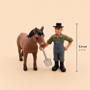 May include: A miniature farm scene featuring a brown horse and a farmer figurine. The farmer, wearing overalls and a hat, holds a pitchfork. The scene is approximately 2.17 inches (5.5 cm) tall, as indicated by the measurement guide.
