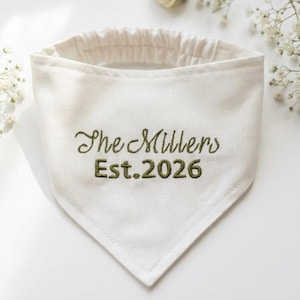 Peut inclure: Un bandana triangulaire pour animal de couleur cr&egrave;me avec un tour de cou &eacute;lastique. Le tissu est brod&eacute; du texte vert fonc&eacute; "The Millers" sur la ligne sup&eacute;rieure et "Est. 2026" sur la ligne inf&eacute;rieure en police cursive et b&acirc;ton.