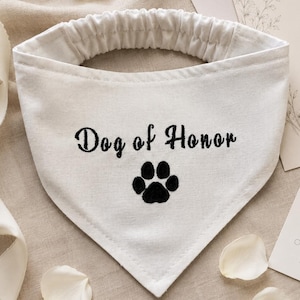 Pu&ograve; includere: Una bandana triangolare bianca per animali domestici con apertura elastica per il collo. Il tessuto &egrave; ricamato con il testo nero "Dog of Honor" posizionato sopra una grafica di un'impronta nera, creando un design chiaro e leggibile per l'accessorio.
