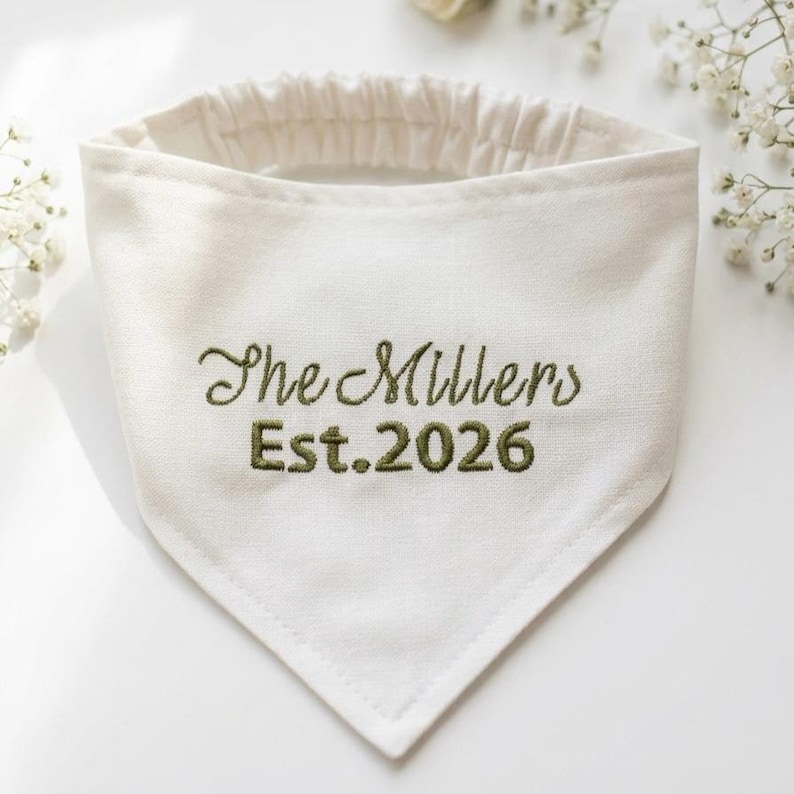Peut inclure: Un bandana triangulaire pour animal de couleur cr&egrave;me avec un tour de cou &eacute;lastique. Le tissu est brod&eacute; du texte vert fonc&eacute; "The Millers" sur la ligne sup&eacute;rieure et "Est. 2026" sur la ligne inf&eacute;rieure en police cursive et b&acirc;ton.