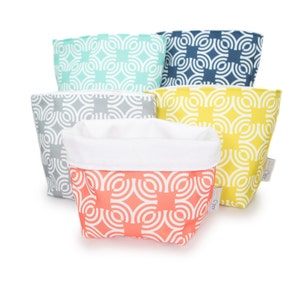 May include: Five fabric zippered pouches in various colors with a geometric pattern. The pouches are stacked on top of each other. The colors are teal, gray, yellow, and coral.